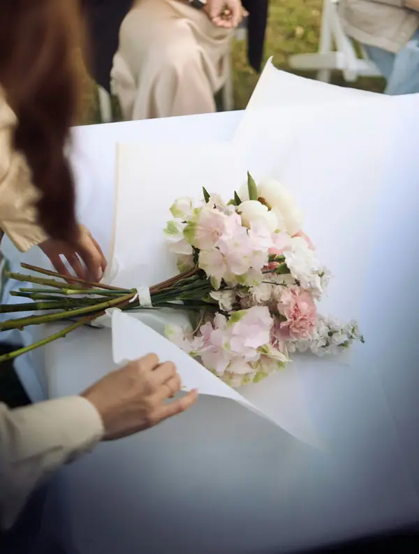 Florist wrapping a pink and white bouquet in paper