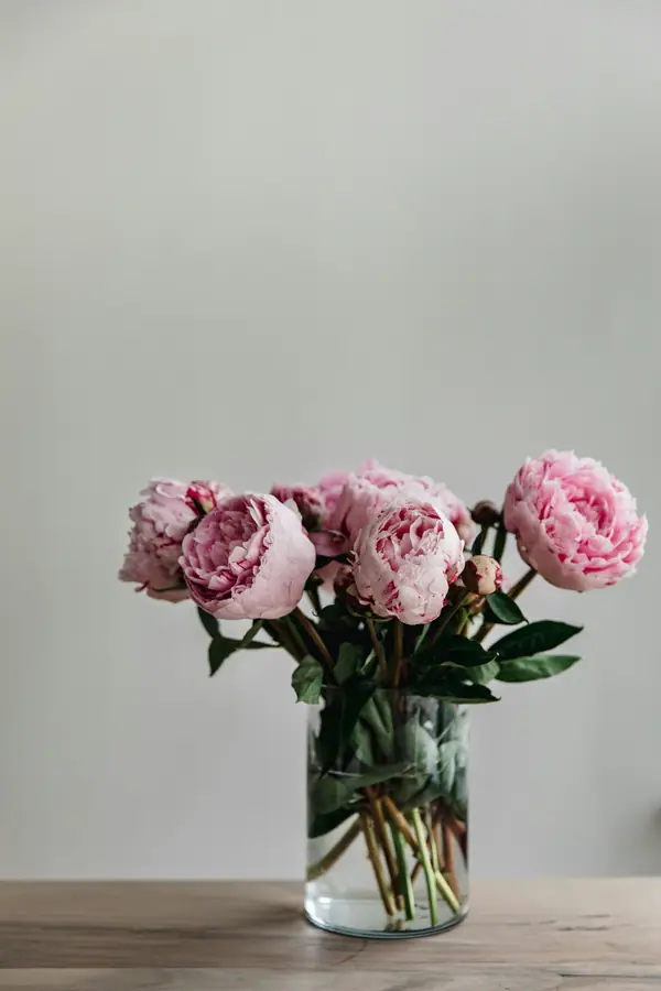 Pink peonies in a glass jar on a wooden table