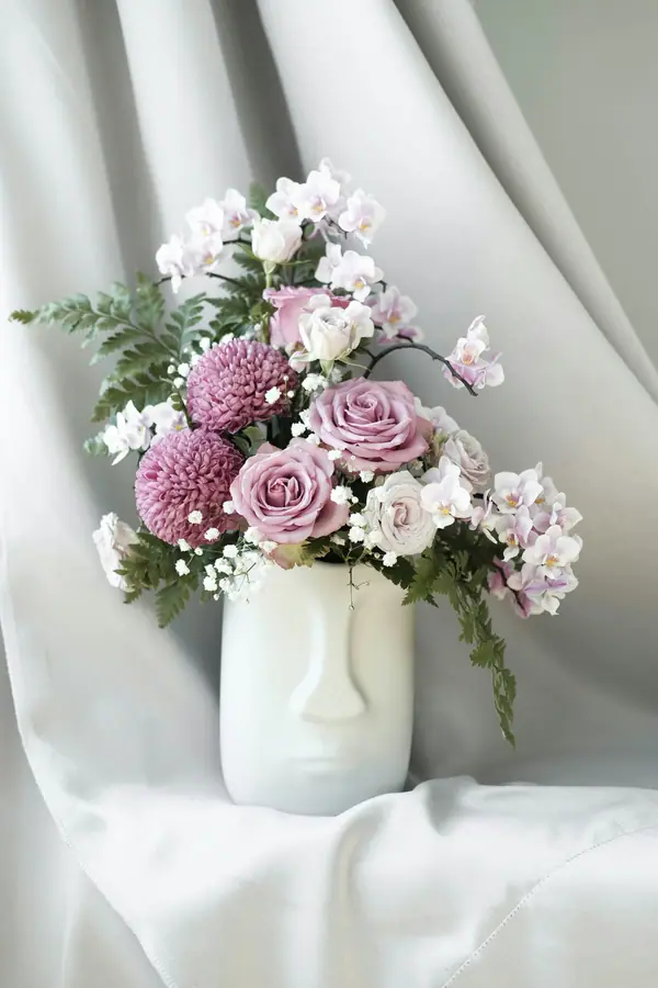 Lilac and white flowers in a sculptural white ceramic vase