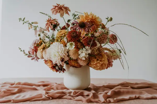 Autumn arrangement of peach and rust flowers in a white vase