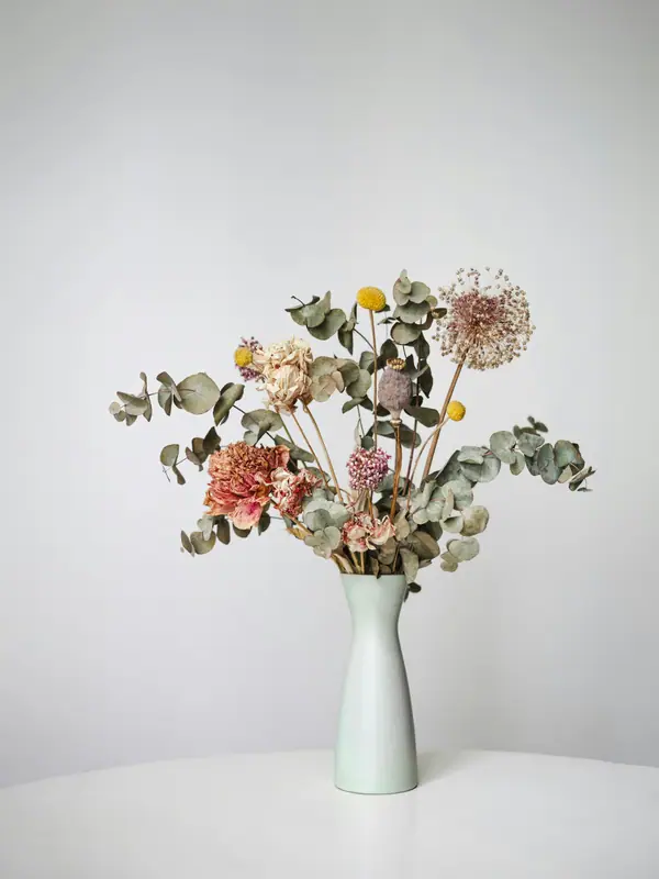 Airy arrangement of eucalyptus and muted blooms in a white vase