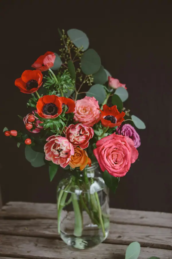 Coral and red flowers with greenery in a glass vase