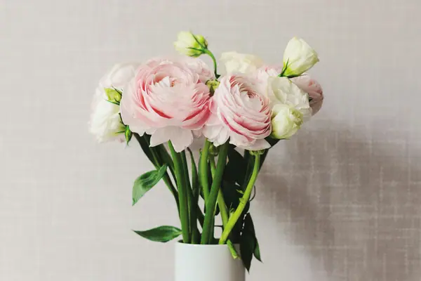 Pink and white ranunculus in a small white vase