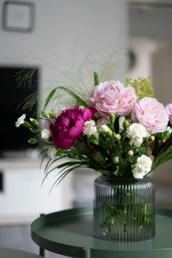 Soft pink and white flowers in a ribbed glass vase