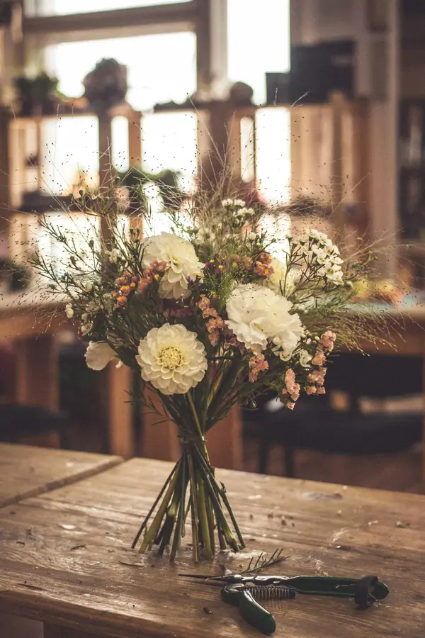 Arrangement of cream and blush flowers on a wooden table in a flower studio