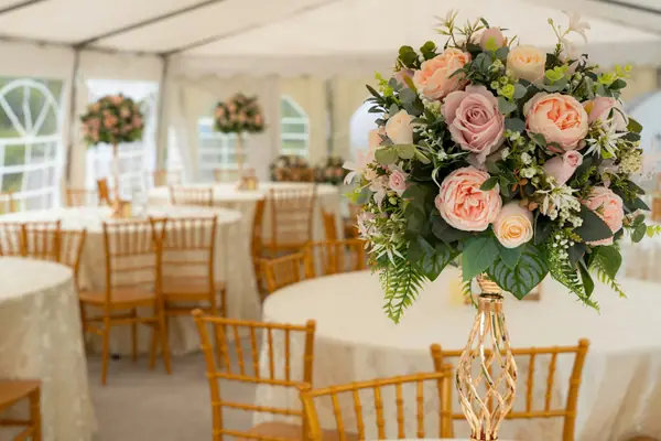 Tall rose centerpiece on a reception table in an event tent