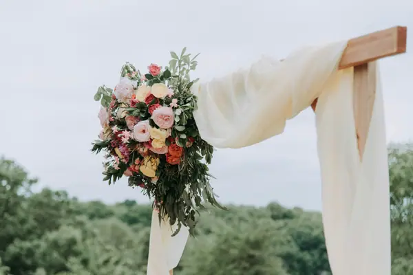 Ceremony arch with draped fabric and a floral cluster